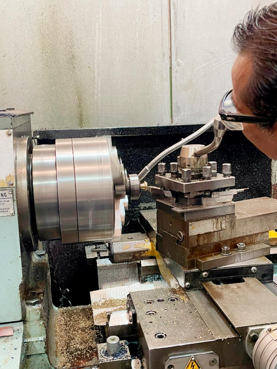 Operador verificando una pieza durante el maquinado en un taller CNC